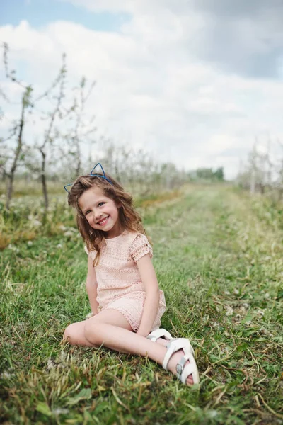 Vacker liten flicka i blommande trädgård — Stockfoto