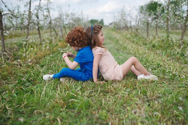 Liten pojke och flicka i blommande trädgård — Stockfoto
