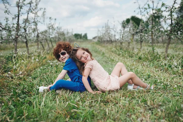 Menino e menina no jardim florescendo — Fotografia de Stock