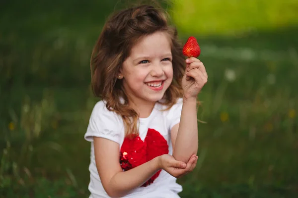 Menina bonita comer grande morango suculento — Fotografia de Stock