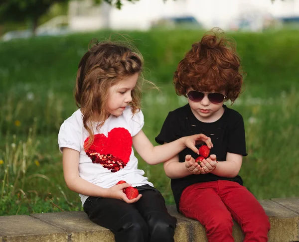 Engraçado menino e menina partilha de morango — Fotografia de Stock