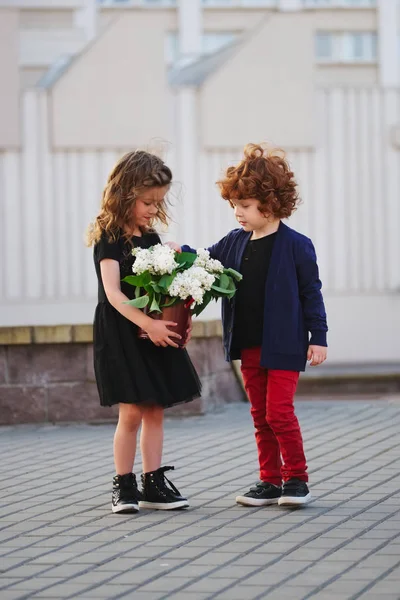 Kleiner Junge und Mädchen mit großem fliederfarbenen Strauß — Stockfoto