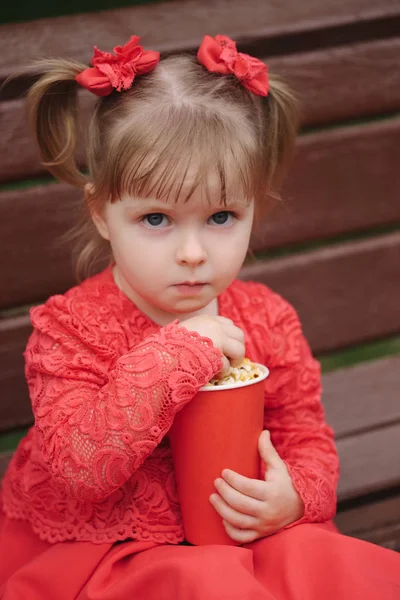 Little girl with cup of popcorn in park — Stock Photo, Image