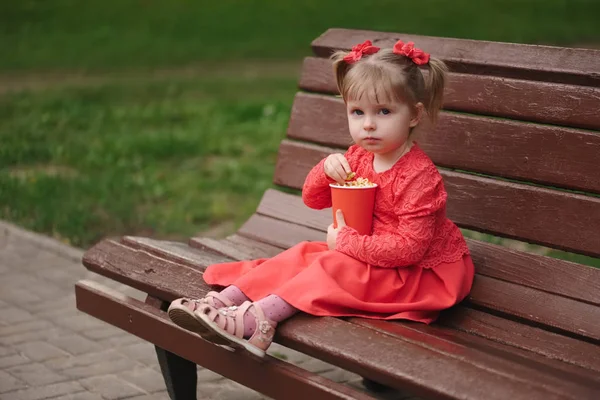 Kleines Mädchen mit Tasse Popcorn im Park — Stockfoto