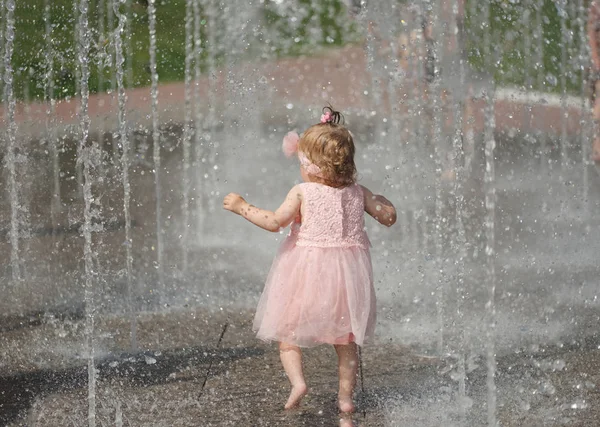 Маленькая девочка играет с водой в фонтане — стоковое фото