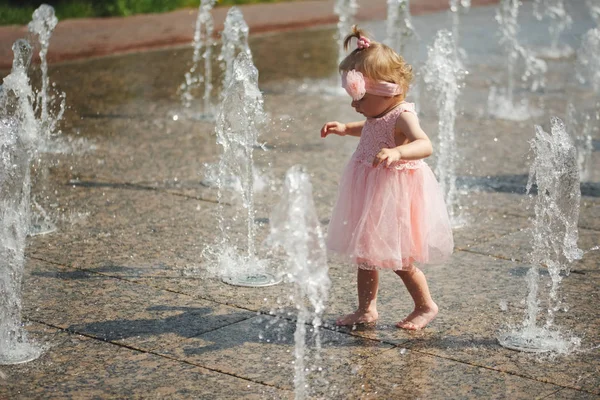 Liten flicka leker med vatten i fontänen — Stockfoto