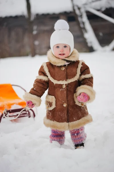 Nettes Mädchen mit Schlitten im Schnee — Stockfoto