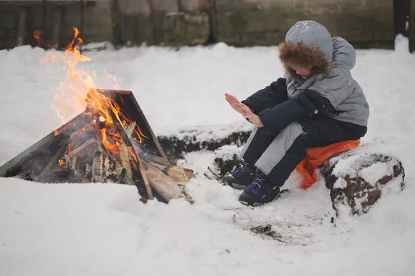 boy sitting by fire in the street