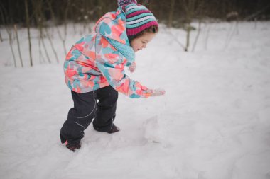 Kız kardan adam kış parkta yapar.