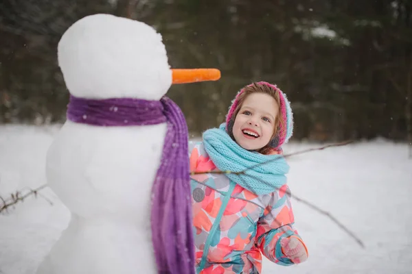 女孩做雪人在冬天公园 — 图库照片