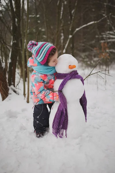 Dziewczyna sprawia, że snowman w winter park — Zdjęcie stockowe