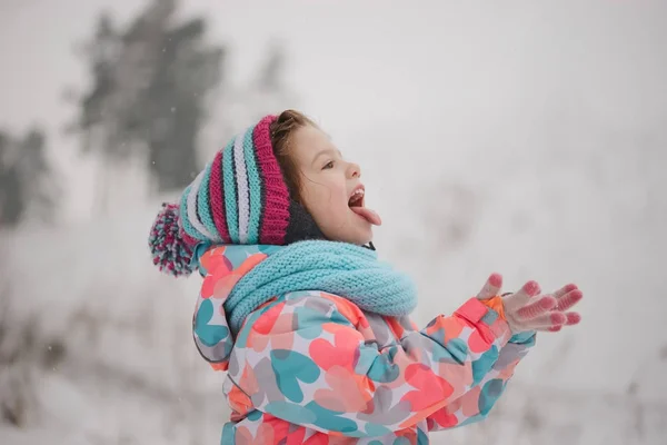 Little girl catching snowflakes in winter park — Stock Photo, Image