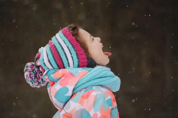 Μικρό κορίτσι που πιάνει νιφάδες χιονιού στο χειμώνα πάρκο — Φωτογραφία Αρχείου