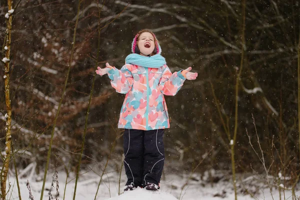 Μικρό κορίτσι που πιάνει νιφάδες χιονιού στο χειμώνα πάρκο — Φωτογραφία Αρχείου