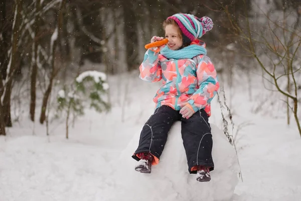 Dziewczyna sprawia, że snowman w winter park — Zdjęcie stockowe