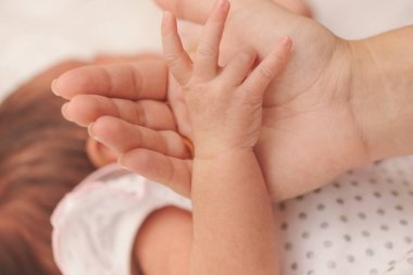 Anne yeni doğan bebeğin elini tutar