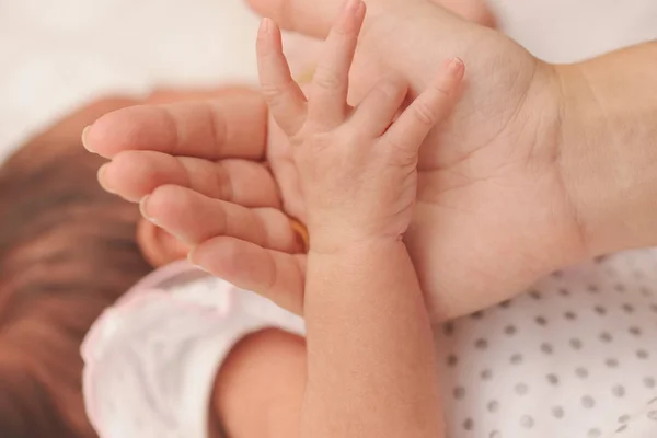 母は、生まれたばかりの赤ちゃんの小さな手を保持しています。 — ストック写真