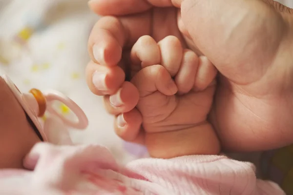 Мати тримає маленьку руку новонародженої дитини — стокове фото