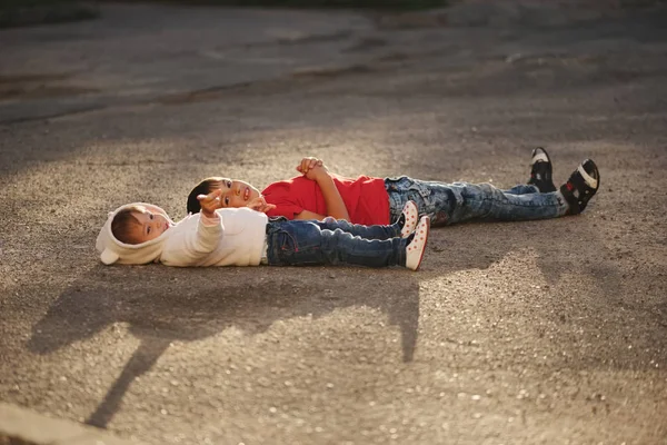 Niño y niña acostados sobre asfalto — Foto de Stock