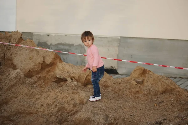 Girl plays with sand on construction — Stock Photo, Image