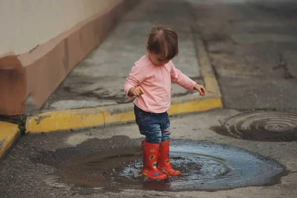 女の子が屋外の水たまりで遊ぶ — ストック写真