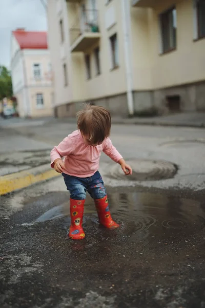 女の子が屋外の水たまりで遊ぶ — ストック写真