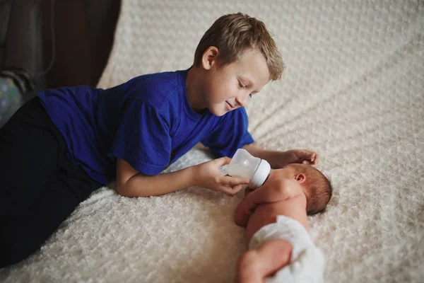 Bambino che alimenta il neonato con una bottiglia di latte — Foto Stock