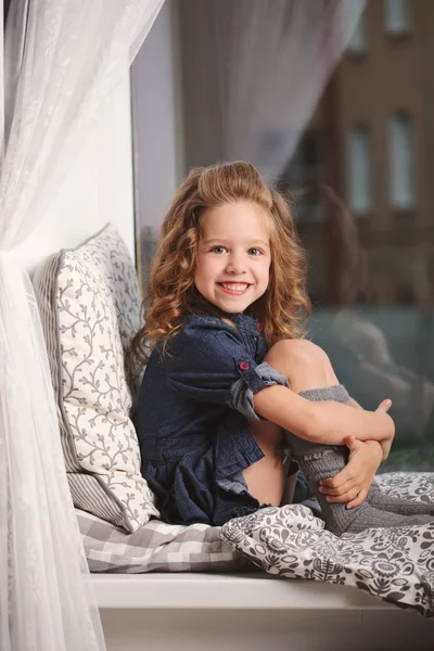 Niña en el alféizar de la ventana en casa — Foto de Stock