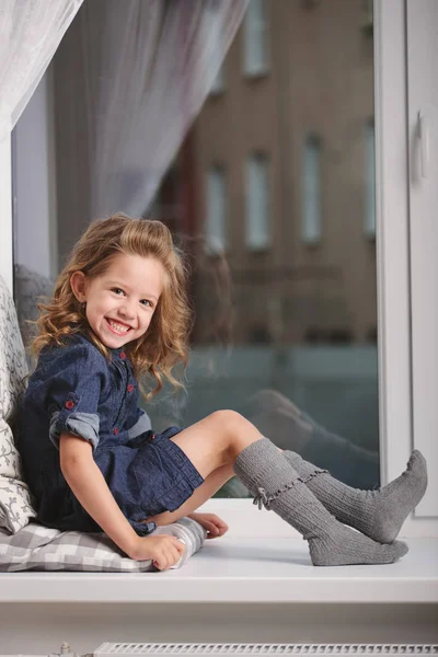 Niña en el alféizar de la ventana en casa —  Fotos de Stock