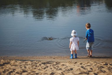 erkek ve kız nehir kıyısında çubuk ile