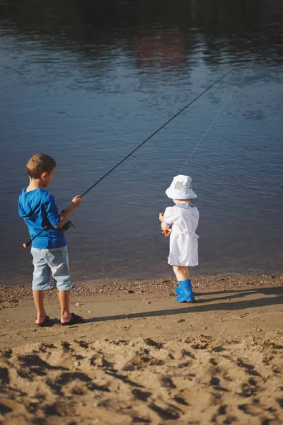 Garçon et fille avec tige sur la côte de la rivière — Photo