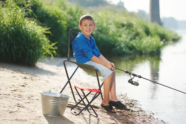 Niño feliz con varilla en la costa del río — Foto de Stock