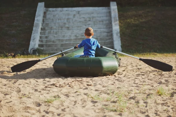 Liten pojke simning i båt på sandstrand — Stockfoto