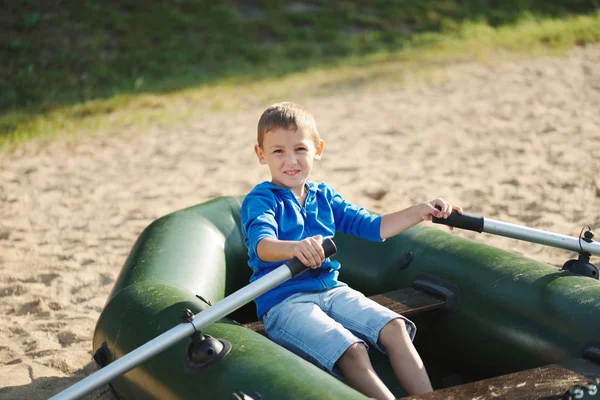 Маленький мальчик плавает в лодке на песчаном пляже — стоковое фото
