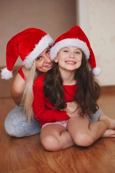 Schöne Mutter und Tochter mit Weihnachtsmützen — Stockfoto