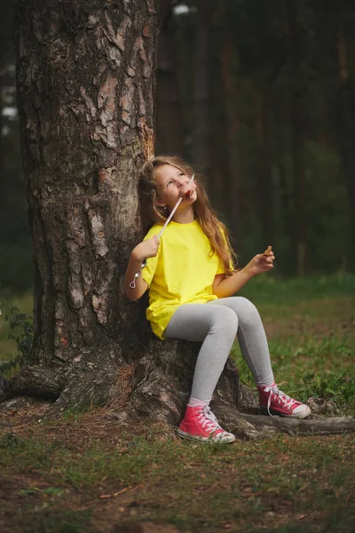 Girl eats sausage in summer forest — Stock Photo, Image