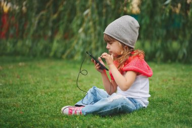 Çimlerin üstünde hareket eden telefon ile küçük kız