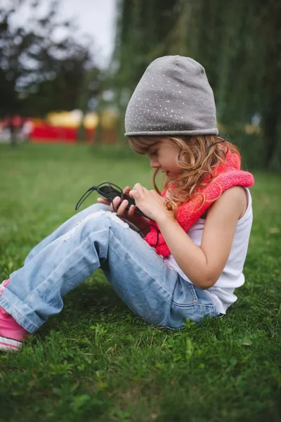 Маленькая девочка с мобильным телефоном на траве — стоковое фото