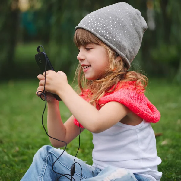 Niña con teléfono móvil en la hierba — Foto de Stock