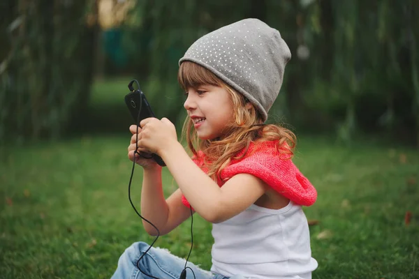 Niña con teléfono móvil en la hierba — Foto de Stock