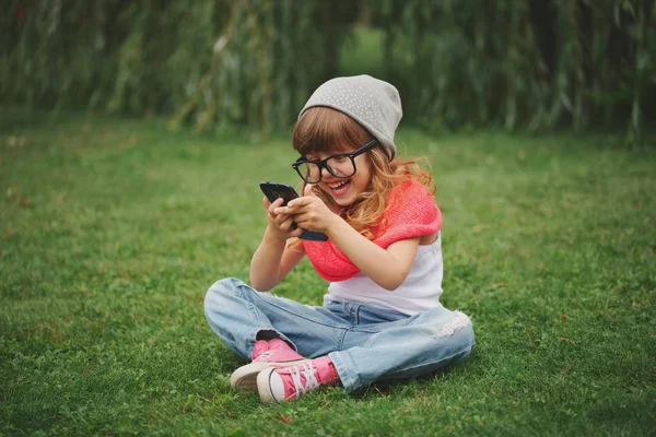 Niña con teléfono móvil en la hierba — Foto de Stock