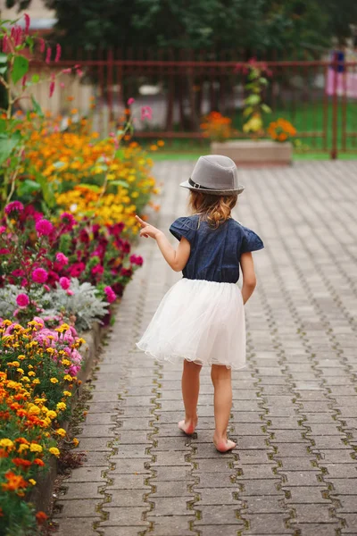 Little beautiful girl in flowers park — Stock Photo, Image