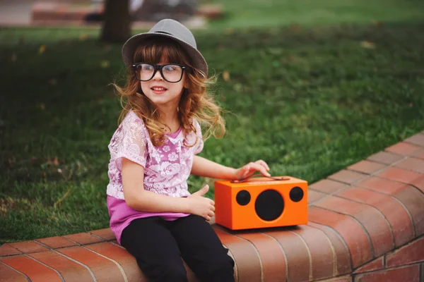 Маленька хіпстерська дівчинка слухає музику на бездротовому ретро дивлячись Spea — стокове фото