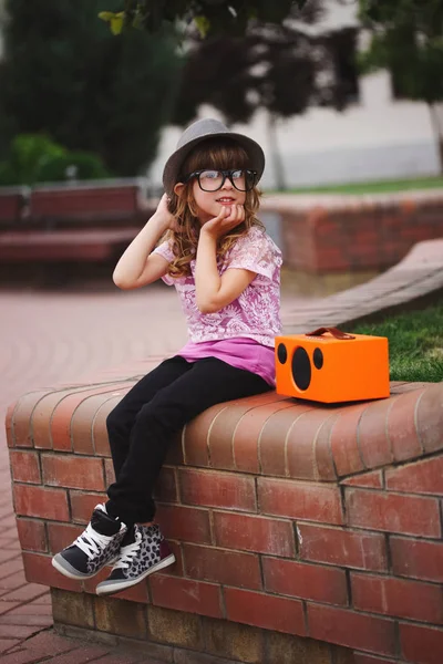 Little hipster girl listens music on wireless retro looking spea — Stock Photo, Image