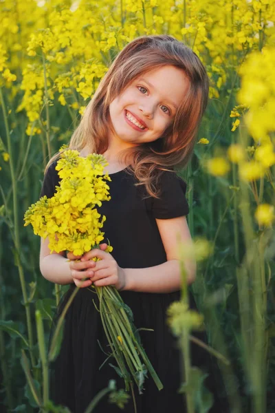 Красивая девушка с желтыми цветами в поле — стоковое фото