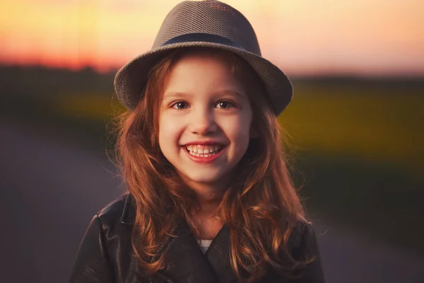 Menina bonita com chapéu no pôr do sol da noite — Fotografia de Stock