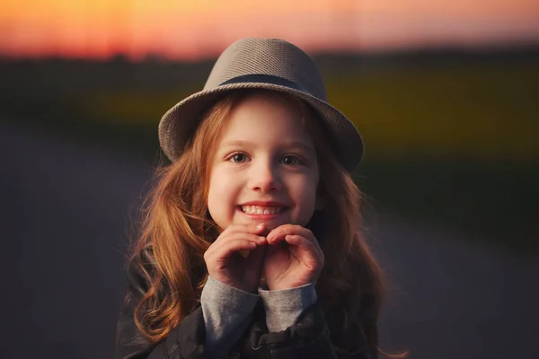 Menina bonita com chapéu no pôr do sol da noite — Fotografia de Stock