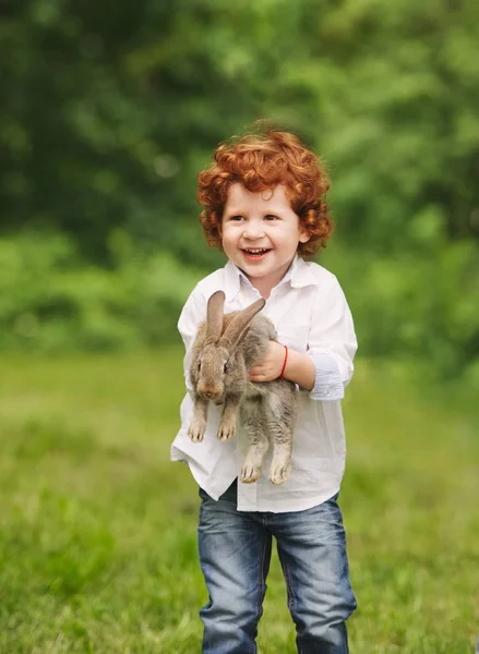 Litle boy gioca con coniglio nel parco — Foto Stock