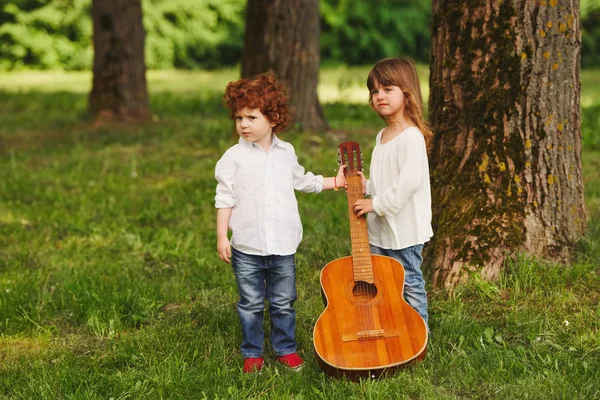 Menino e menina tocando guitarra no parque de verão — Fotografia de Stock