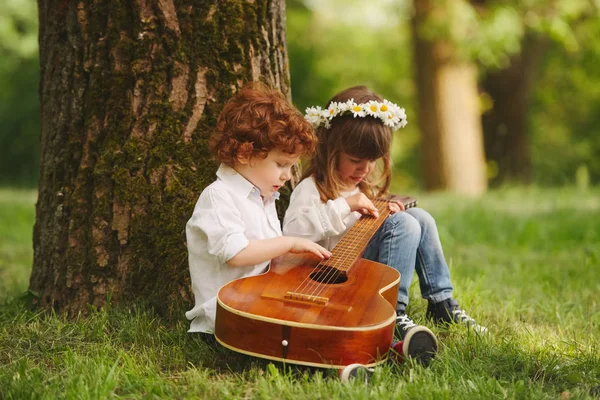 男孩和女孩在夏天公园演奏吉他 — 图库照片